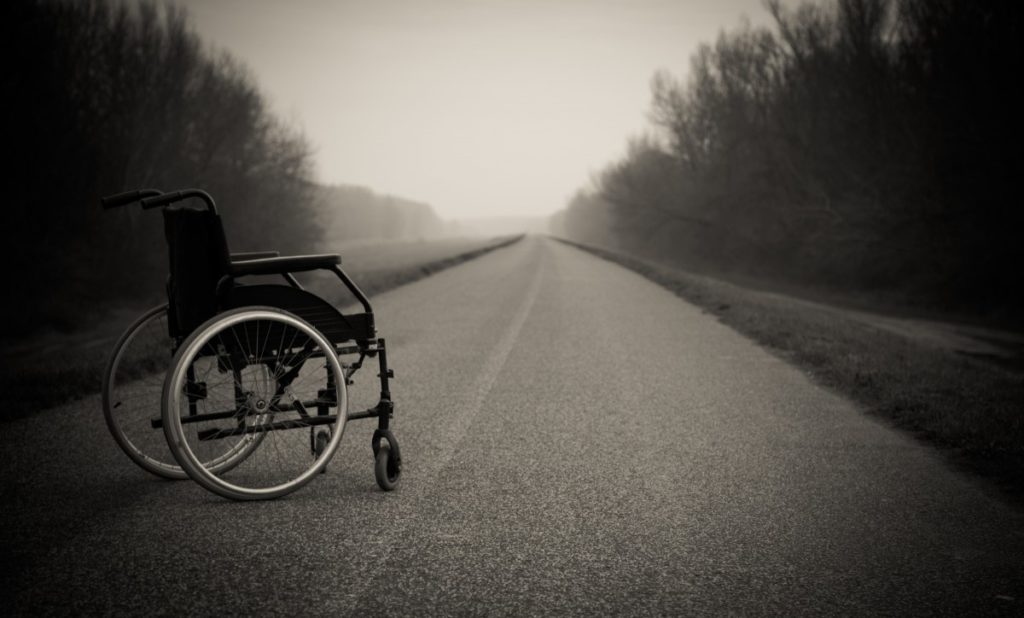 Silla de ruedas en medio de una carretera abandonada. 