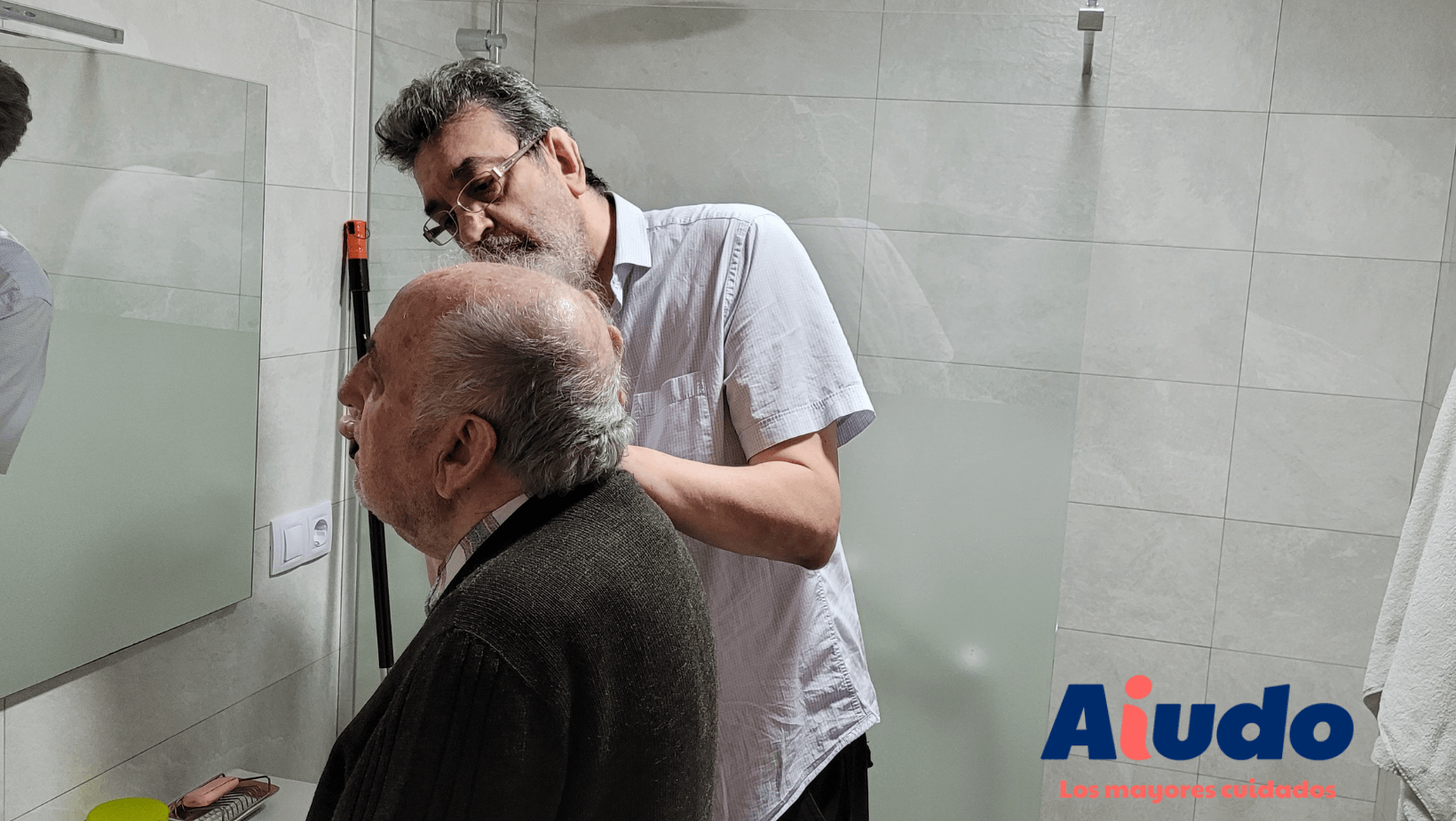 Un cuidador afeita a un señor mayor que sufre problemas de riego sanguíneo y primeros síntomas de párkinson.