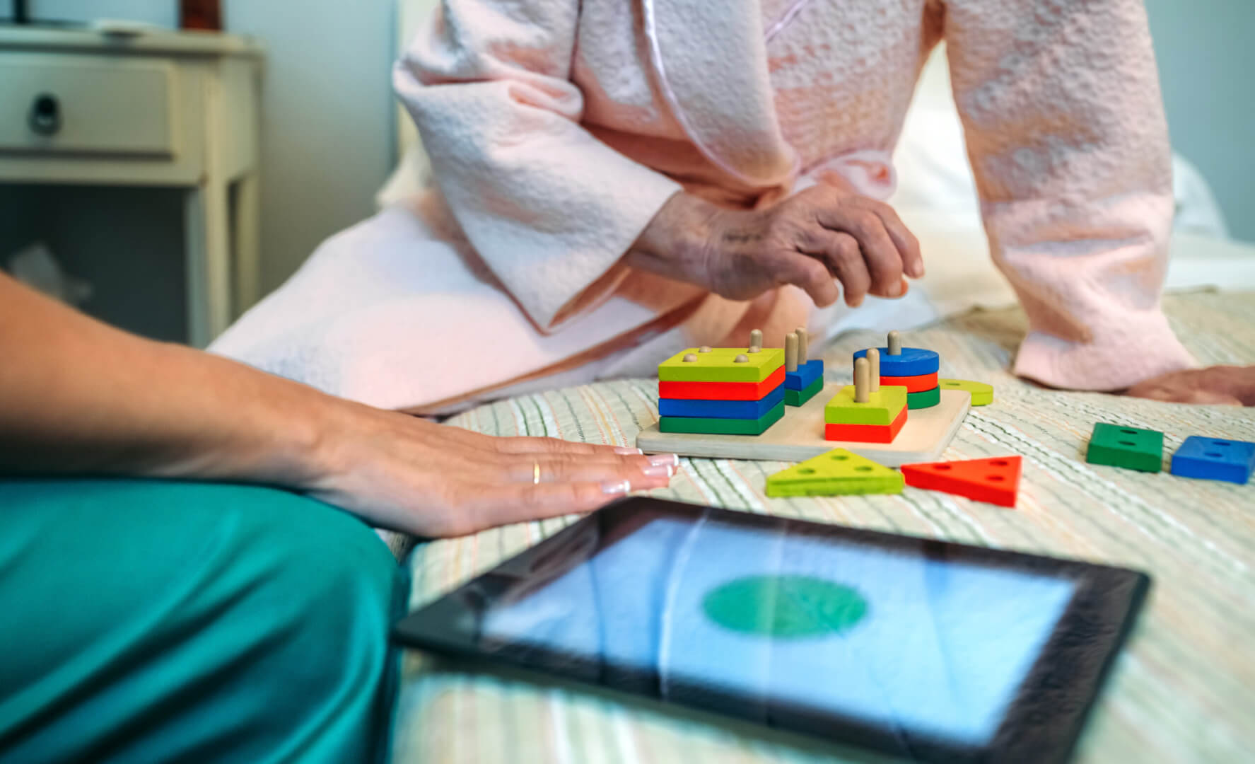 Una anciana y una cuidadora juegan a videojuegos con una tablet. 