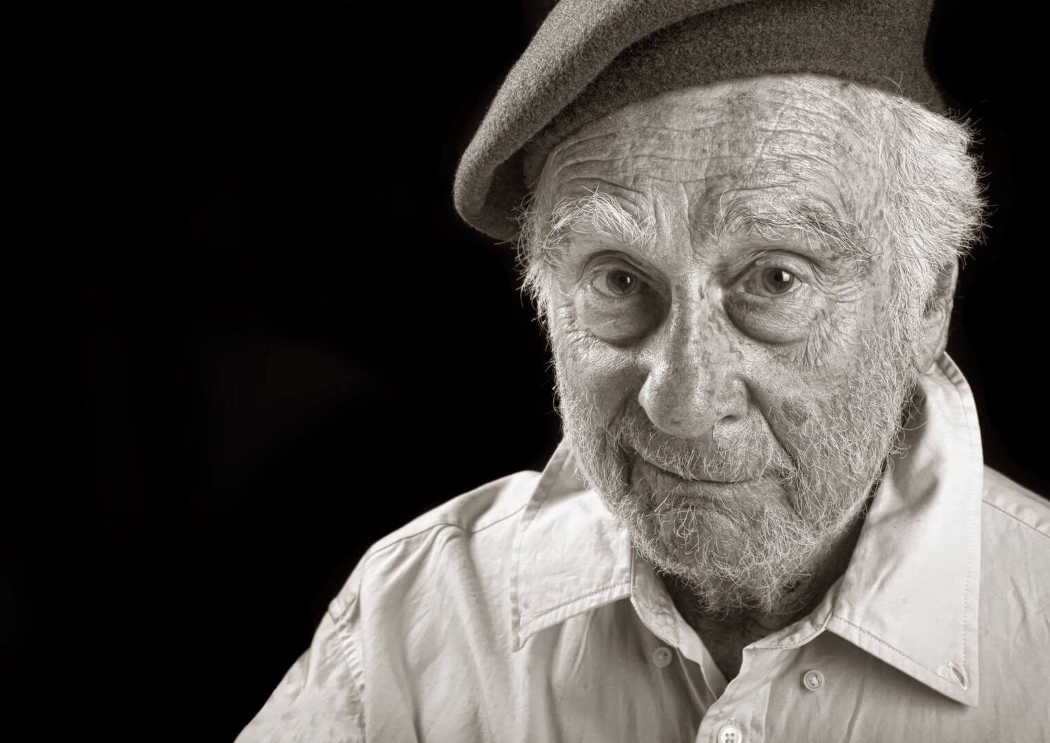 Un hombre mayor posa en una imagen en blanco y negro con una boina.