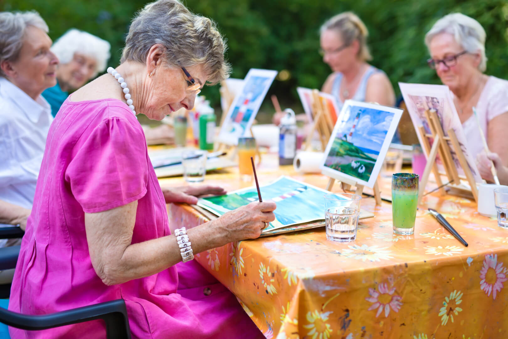 Un taller de pintura con mujeres mayores al aire libre.