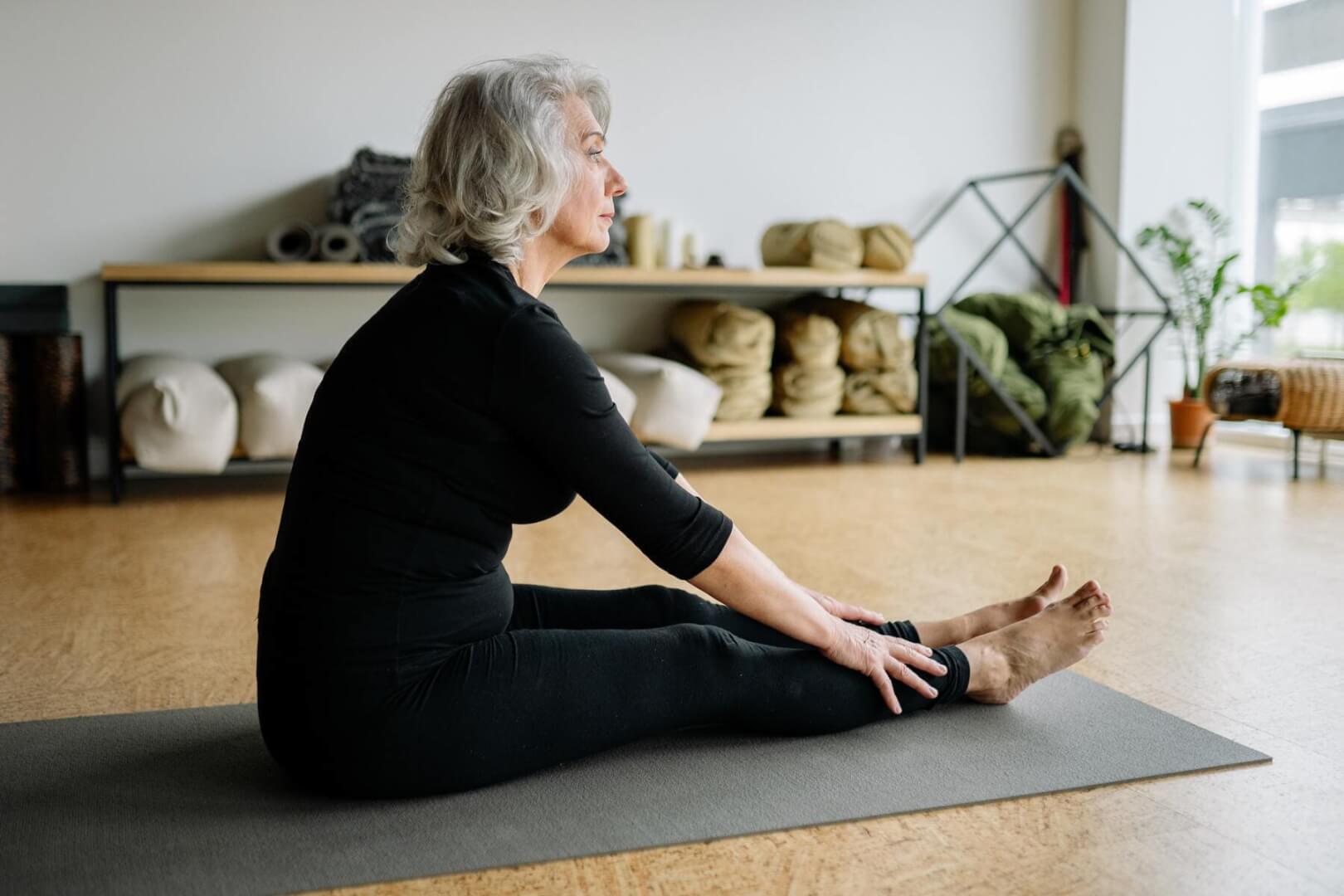 Una mujer mayor tumbada sobre una esterilla practica el mindfulness