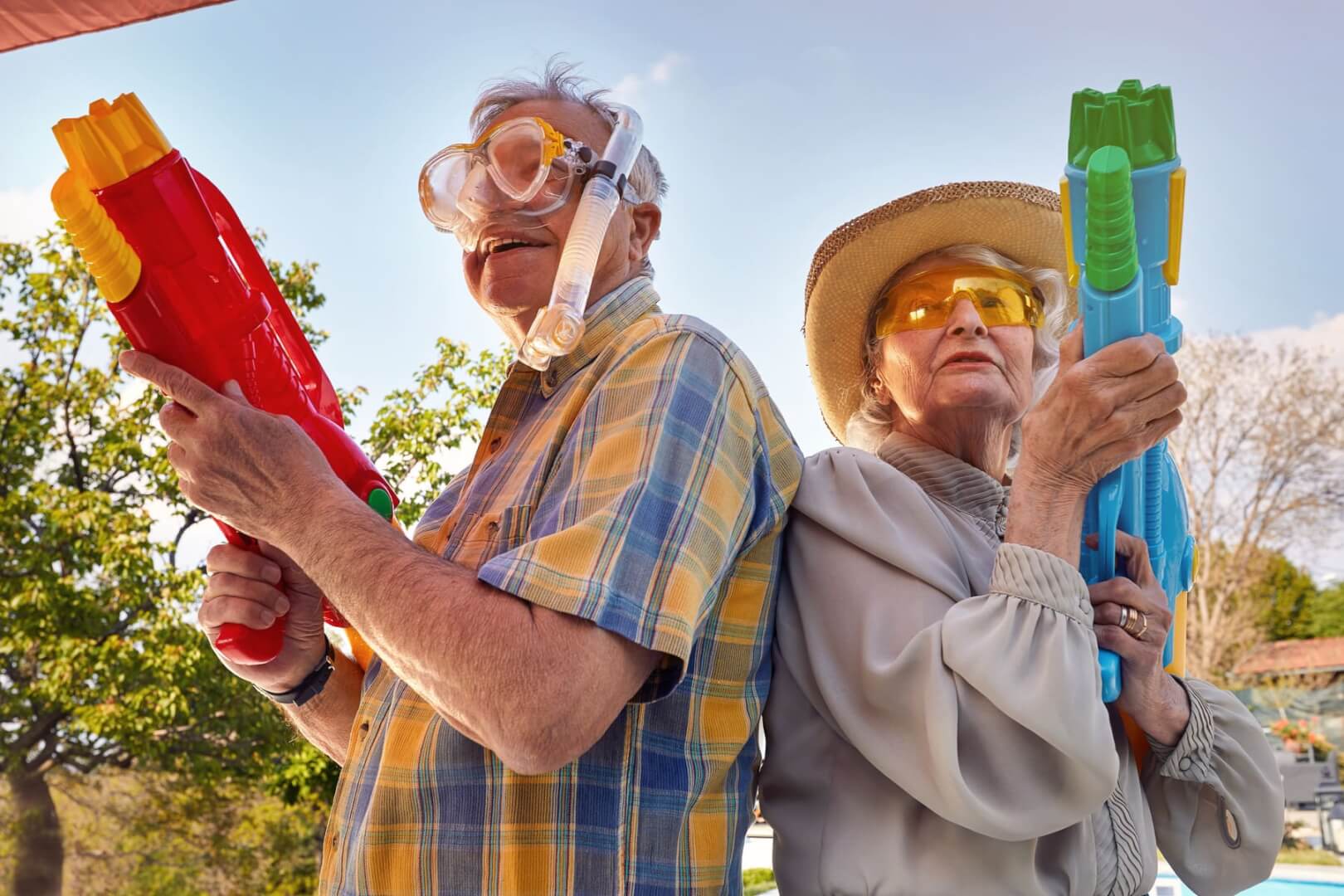 Dos ancianos disfrazados en una fiesta con pistolas de agua.