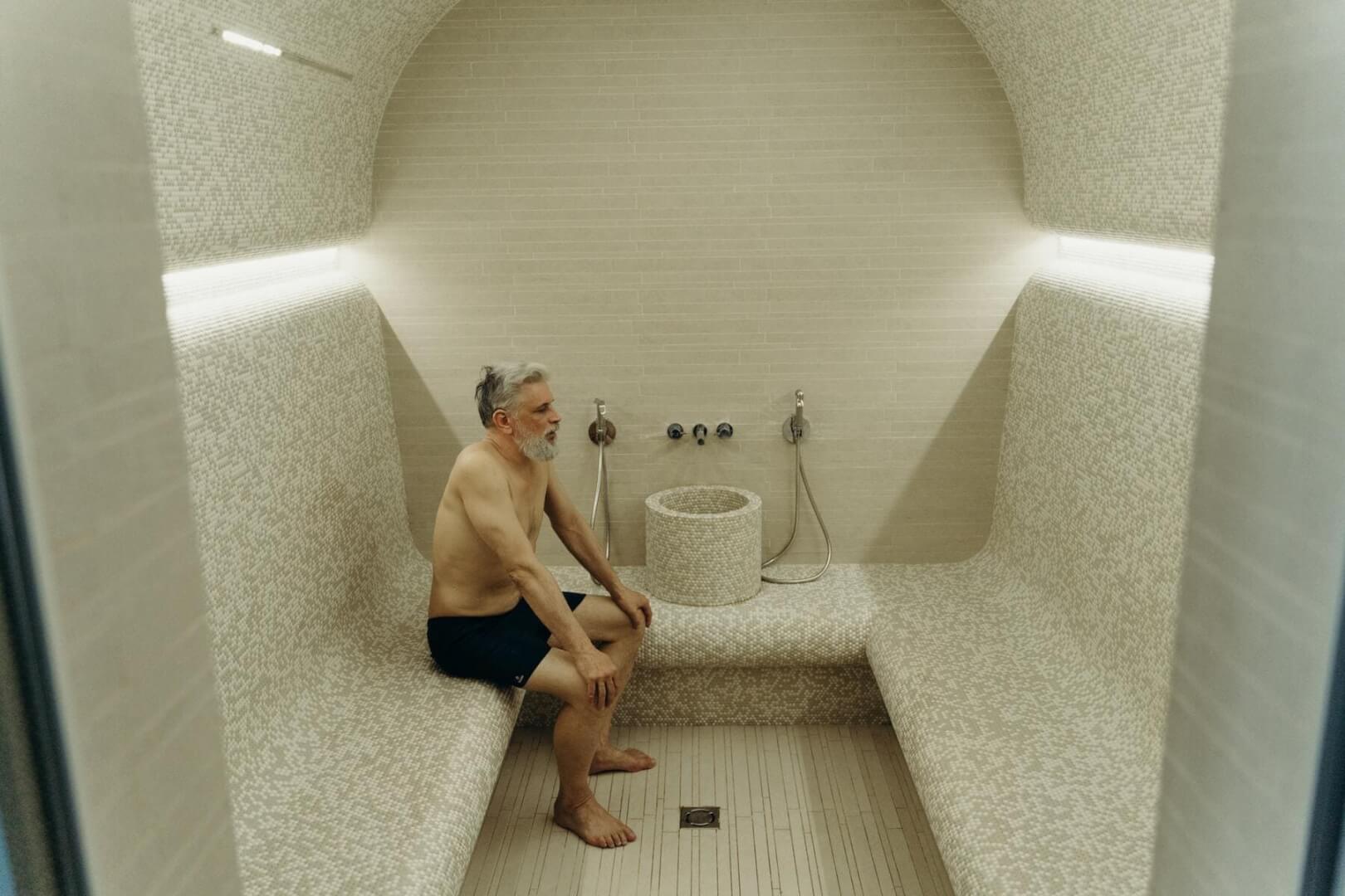 Un anciano sentado en el interior de una sauna.