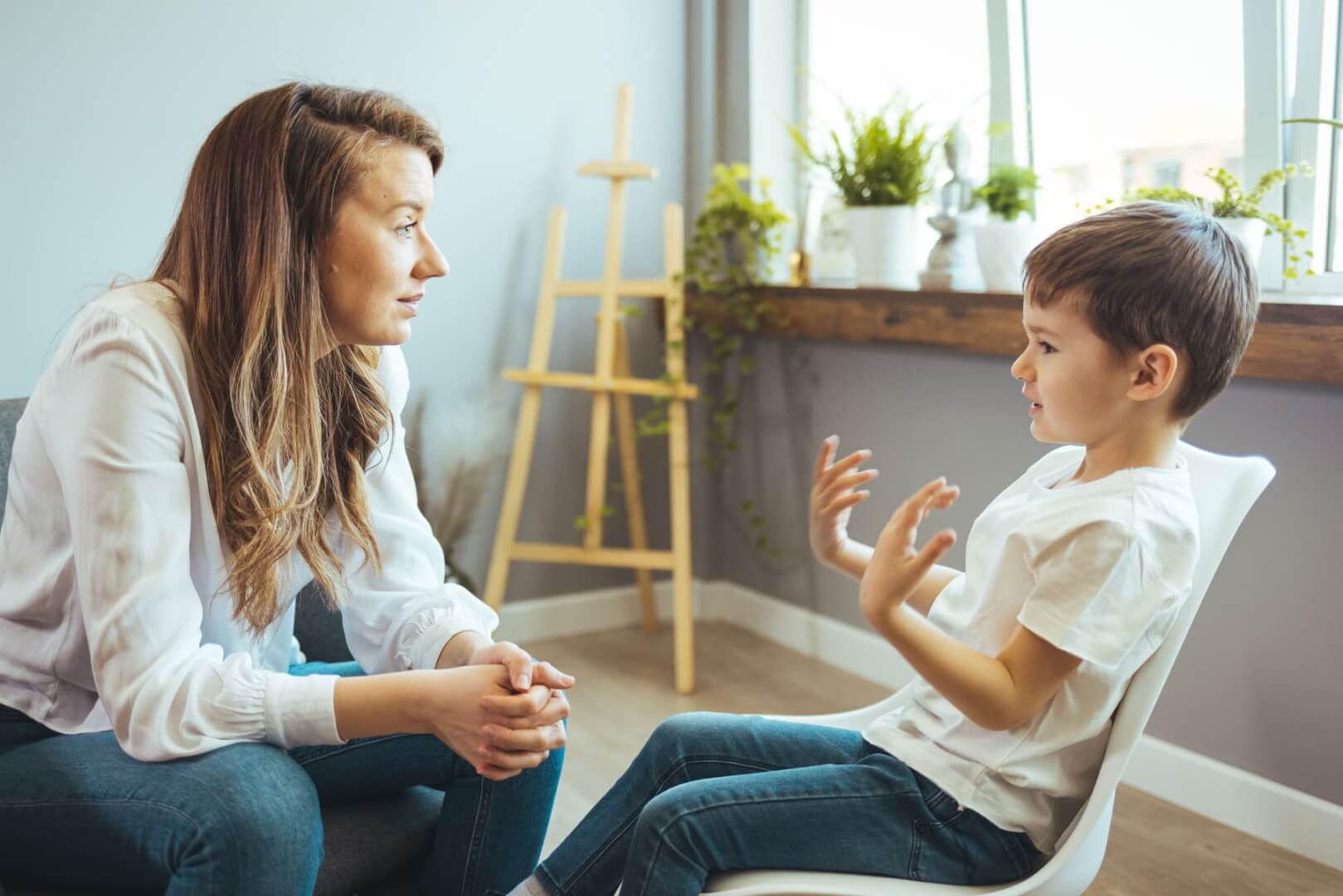 Una cuidadora con un niño pequeño hablan en una habitación. 