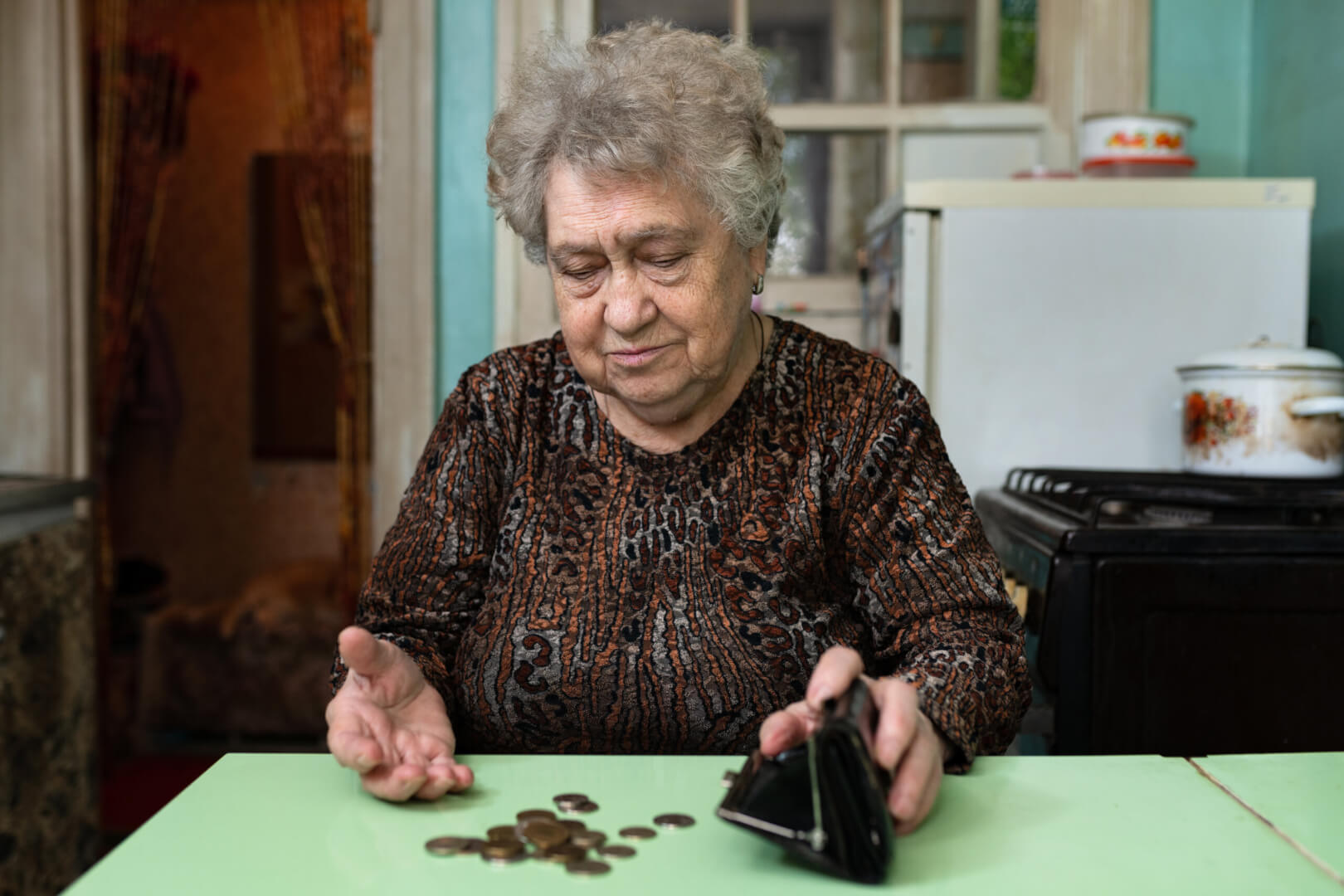 Una anciana mira unas pocas monedas que extrae de su monedero con cara de asombro. 