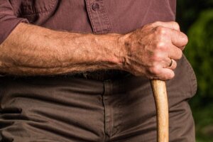 Detalle de un anciano agarrando un bastón 